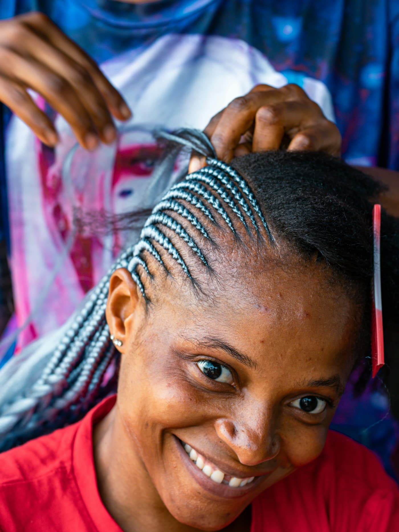 Smiling woman having her hair braided into cornrows