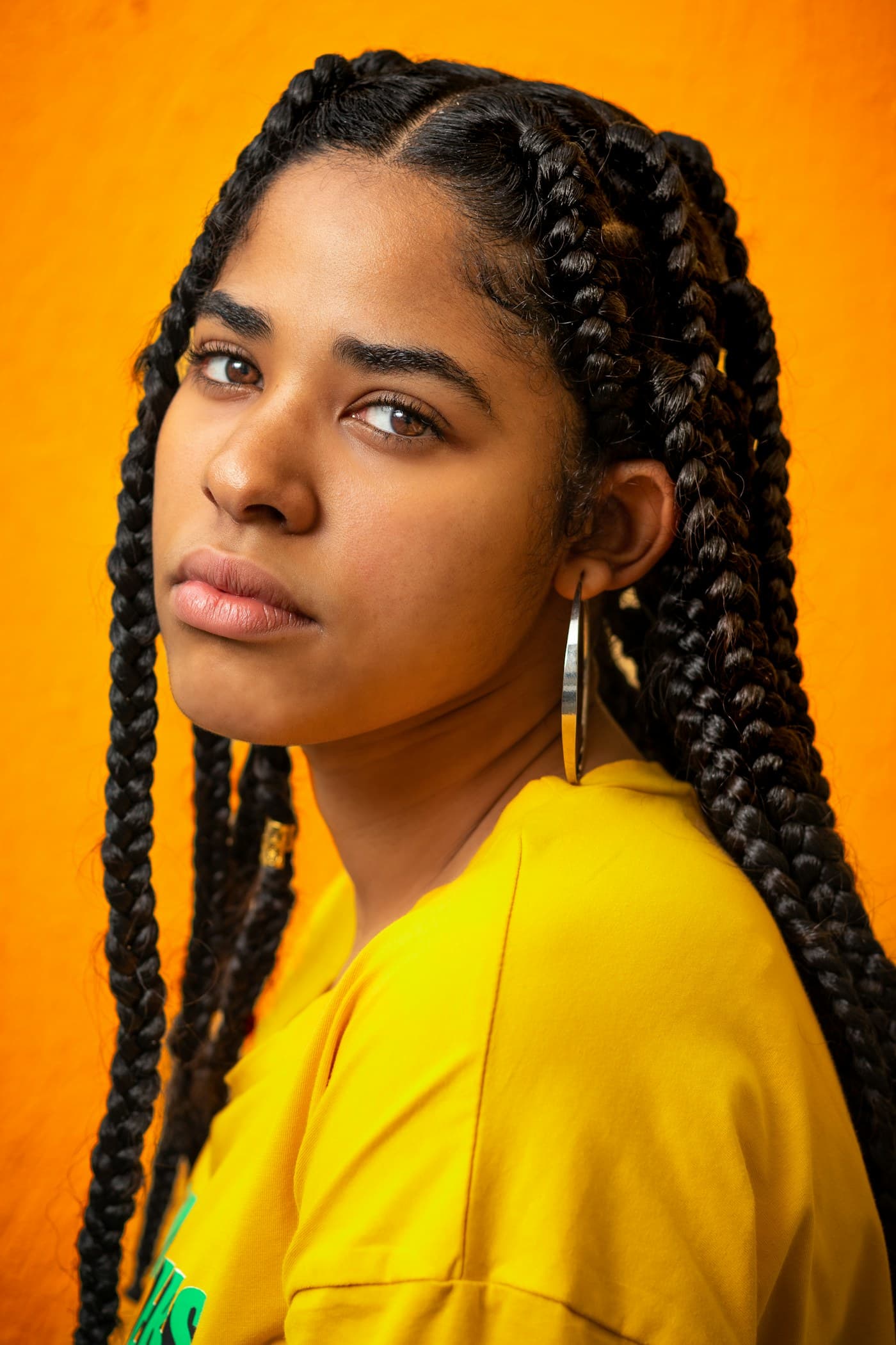 Woman with chunky box braids on orange