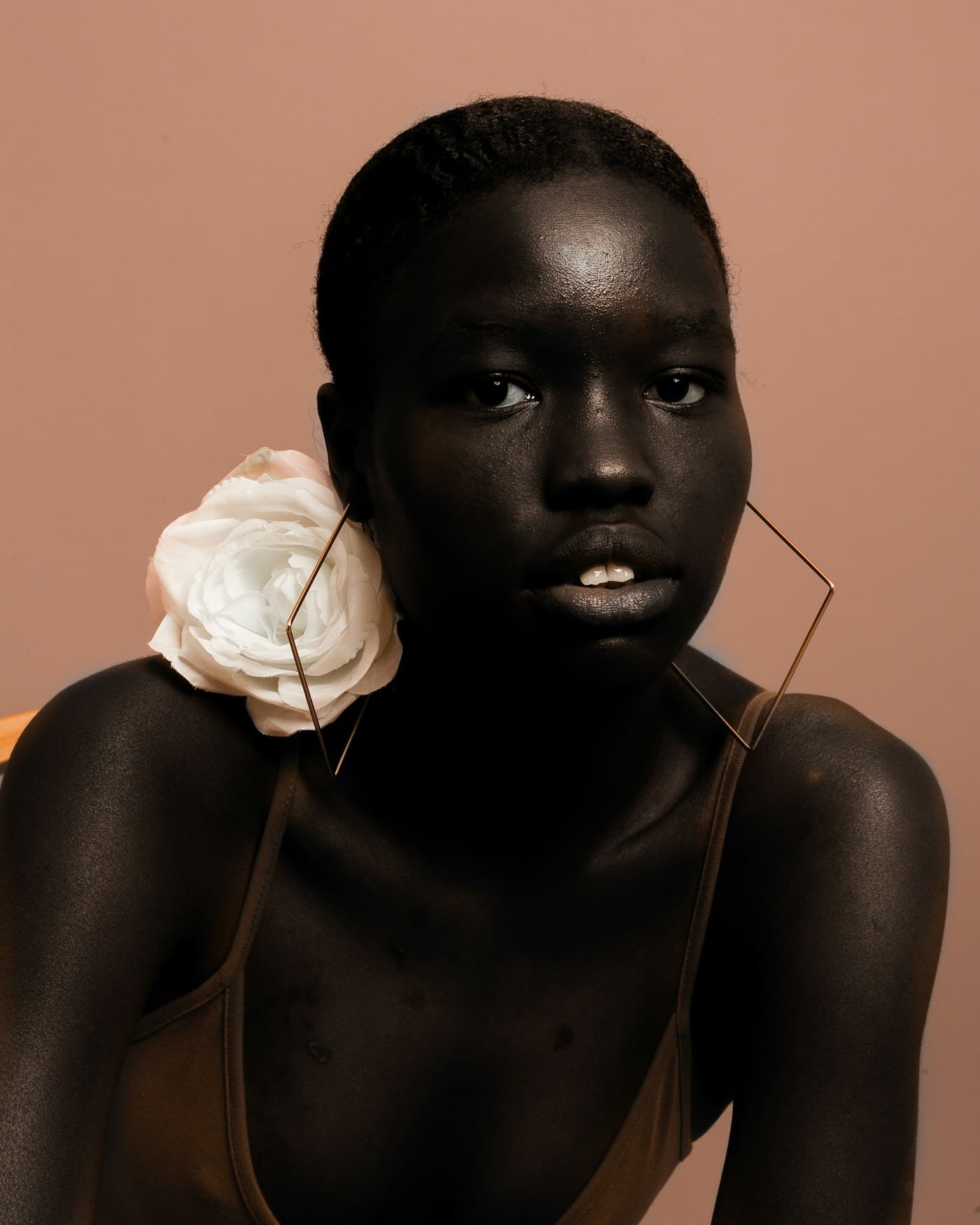 Woman with a white rose and statement earring on blush pink